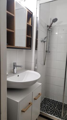 une salle de bain blanche avec un lavabo et une douche dans l'établissement Charmant T2 Béziers centre ville avec balcon, à Béziers