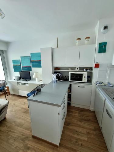 une cuisine avec des armoires blanches et un comptoir dans l'établissement Les Dryades 4 pax appartement, à La Baule