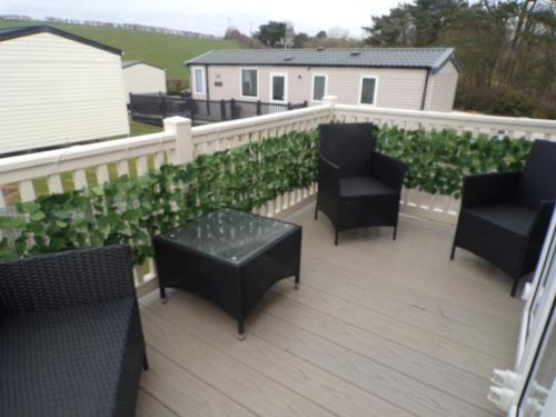 a deck with black chairs and tables and a fence at Margaret's in Wool