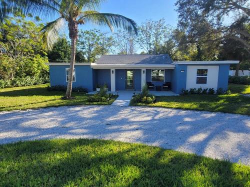 a blue house with a palm tree and a driveway at Jungle in the City! in West Palm Beach