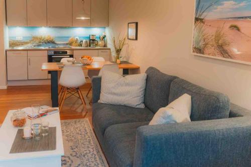 un soggiorno con un divano blu e una cucina di Ferienwohnung Sahel - Inselhof Fehmarn a Fehmarn
