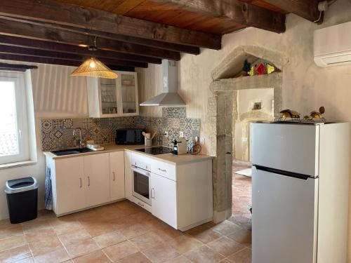une cuisine avec des armoires blanches et un réfrigérateur blanc dans l'établissement Maison de village atypique, à Issirac