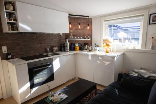 a kitchen with white cabinets and a stove top oven at Cozy studio apartment in Oslo