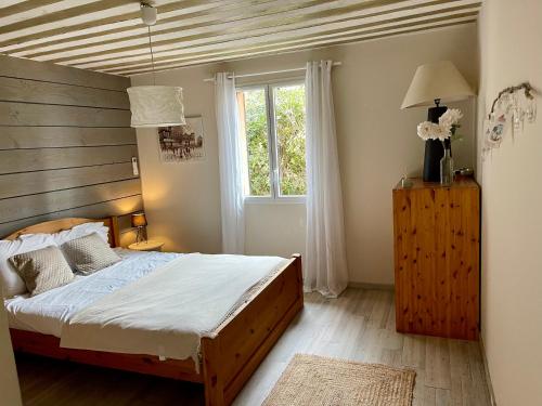 une chambre avec un lit avec une tête de lit en bois et une fenêtre dans l'établissement Le Clos des Fraisiers, à Monteux