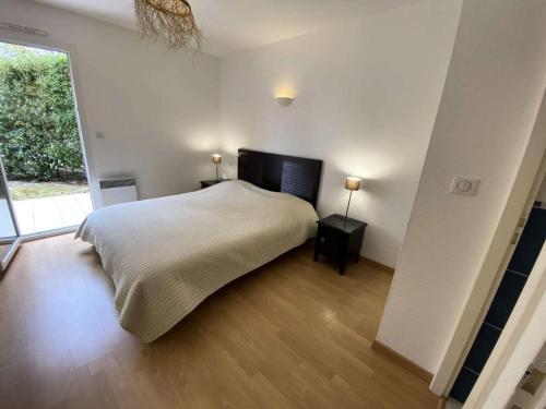 une chambre avec un lit et une grande fenêtre dans l'établissement Résidence Villa Marine - 021- Bel appartement avec son jardin privatif MAE-1841, à Soulac-sur-Mer