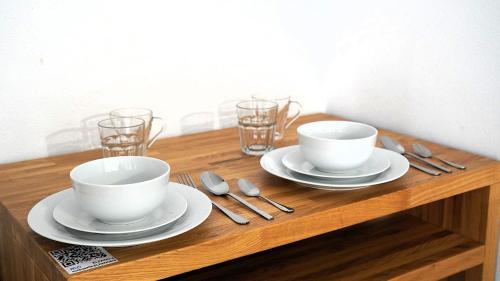 a wooden table with two cups and plates and silverware at El Patio Hostal in Alicante
