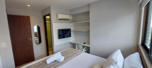 a small white room with a bed and a window at Beach Class Convention - Flats em Boa Viagem por Yolo in Recife