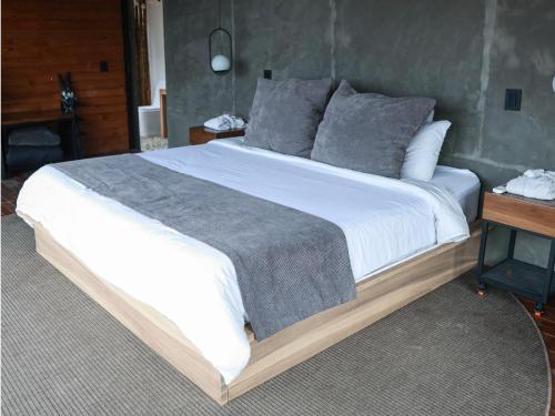 a bedroom with a large bed with white sheets and gray pillows at La Cima Eco Hotel in Buenavista