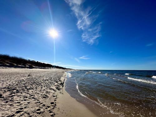 a beach with footprints in the sand and the ocean at Apartment Magnolia Marina Lux & SPA in Dziwnów