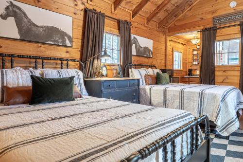 two beds in a room with wooden walls at Northern Acres in Lake George