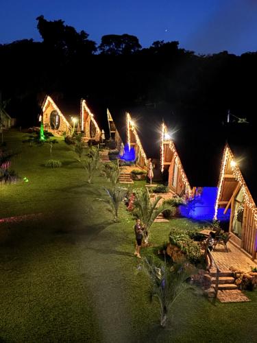 a person standing in front of a group of cottages with lights at Recanto da Natureza in Brotas