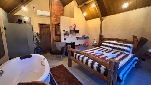 a bedroom with a tub and a bed and a bath room at Recanto da Natureza in Brotas