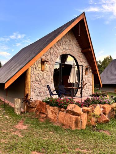 a stone building with a table and an umbrella at Recanto da Natureza in Brotas