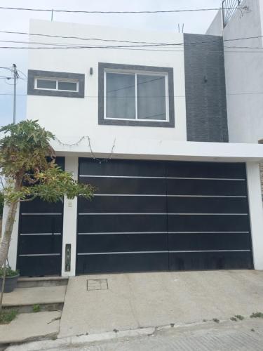 a garage with a black garage door on a house at La casa de wendy in Tuxtla Gutiérrez