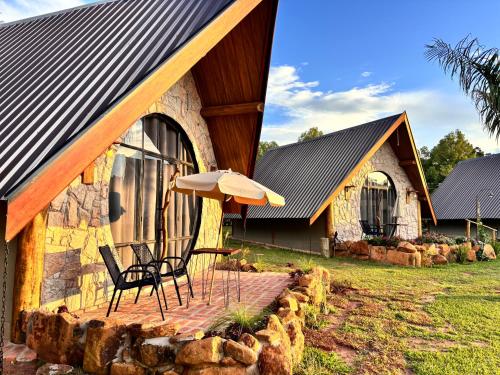 a house with two chairs and an umbrella in front of it at Recanto da Natureza in Brotas