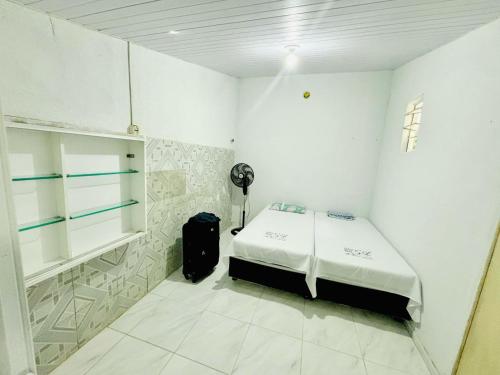 a white room with a bed and a black suitcase at Marcanau in Maracanaú