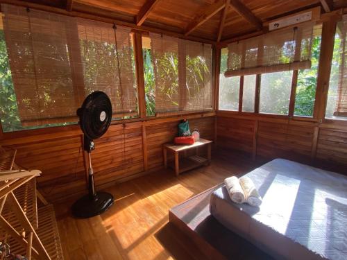 a room with a bed and a fan in a room with windows at Casa Teka a Peaceful Stay Near Beach and Town in Cocles