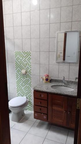 a bathroom with a toilet and a sink and a mirror at Chácara Pedacinho do Céu in Socorro