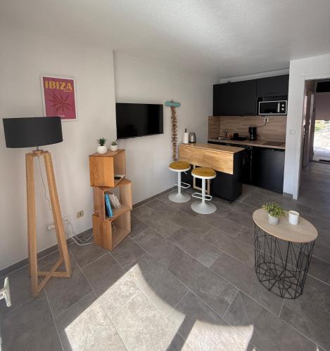 - un salon avec une cuisine dotée d'une table et de tabourets dans l'établissement Studio Cabine Proche Plage de Cavalière, au Lavandou