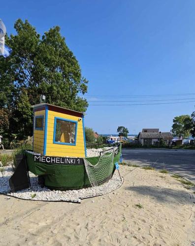 a small boat sitting on the sand on a beach at Mechelinki, Apartament z ogródkiem, widokiem na morze i aneksem kuchennym in Mechelinki