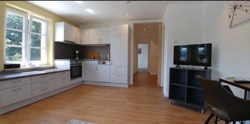 a large kitchen with white cabinets and a television at Villa19hundert5 moderne Ferienwohnungen in zentraler Lage in Lindenberg im Allgäu