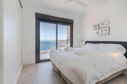 a bedroom with a large bed and a large window at RentitSpain Playa, piscina y terraza al mar in La Herradura