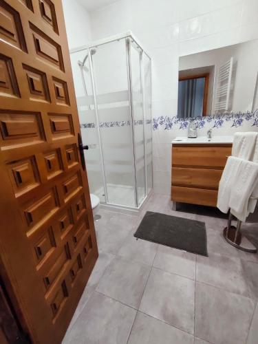 a bathroom with a shower and a wooden door at Casa Capricho del Destino in Villatobas