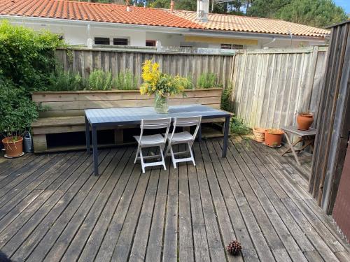 une table bleue et deux chaises blanches sur une terrasse dans l'établissement Appartement piscine Cap Ferret 50m du Bassin et des commerces, à Lège-Cap-Ferret