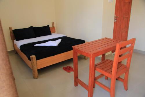 a bedroom with a bed with a wooden table and a chair at Kisoro Comfort Inn in Kisoro
