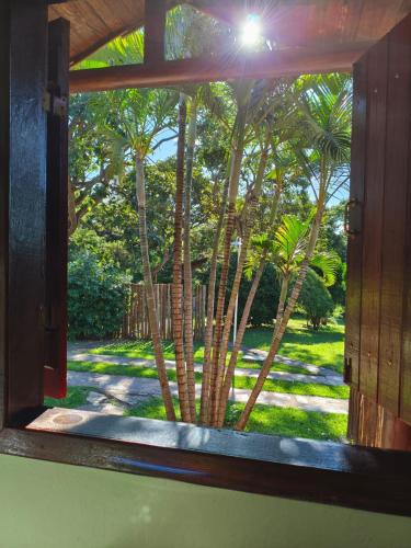 a window view of a yard with palm trees at Pousada Chalés Jardim Da Serra Do Cipó in Serra do Cipo