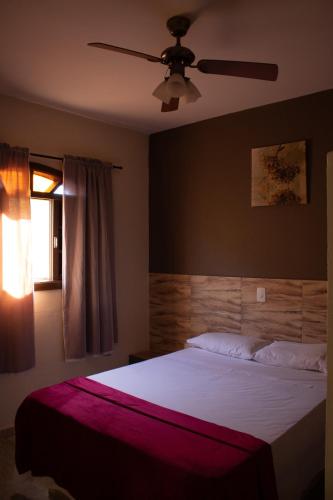 a bedroom with a bed with a ceiling fan at Pousada Campestre Estância São Domingos in Serra Negra