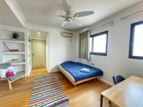 a bedroom with a bed and a table and a ceiling fan at Beautiful Penthouse w/amazing View, Prime location in Ramat Gan