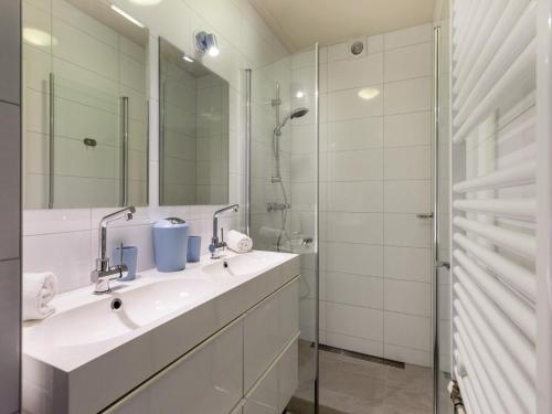 a white bathroom with a sink and a shower at Holiday Home in Zoutelande near Sunny Beach in Zoutelande