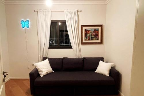 a black couch in a room with a blue butterfly on the wall at Beautiful Penthouse w/amazing View, Prime location in Ramat Gan