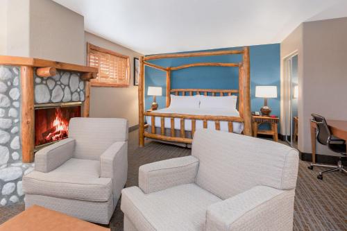 大熊湖的住宿－大熊湖山林小屋假日酒店&度假村，一间卧室配有一张床、两把椅子和一个壁炉