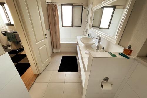 a white bathroom with a sink and a toilet at Beautiful Penthouse w/amazing View, Prime location in Ramat Gan
