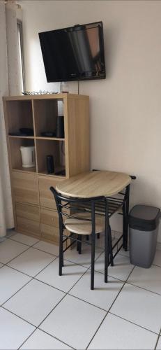 une table avec une chaise et une télévision murale dans l'établissement LOCATION STUDIO EN BORD DE PLAGE A GRUISSAN, à Gruissan