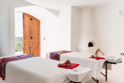 two beds in a room with white walls at NEST Baja in San José del Cabo