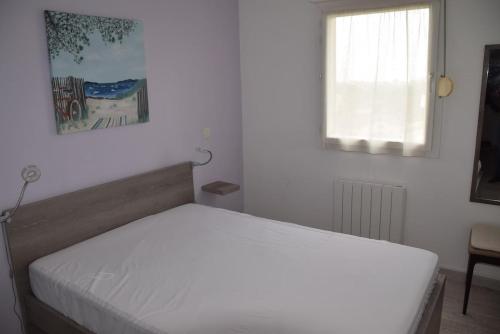 une chambre avec un lit blanc avec une fenêtre dans l'établissement T3 lumineux tout confort aux portes de la Rochelle, à Aytré