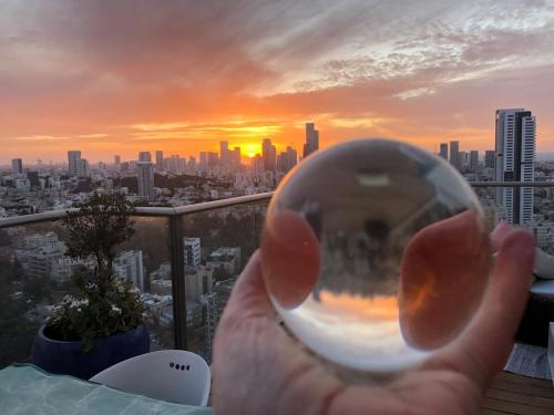 a hand holding a soap bubble in front of a city at Beautiful Penthouse w/amazing View, Prime location in Ramat Gan