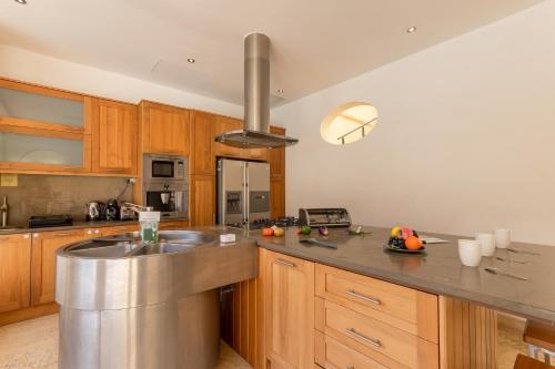 a kitchen with a stainless steel sink and wooden cabinets at OneFifty Gozitan Villa and Pool in Il-Pergla