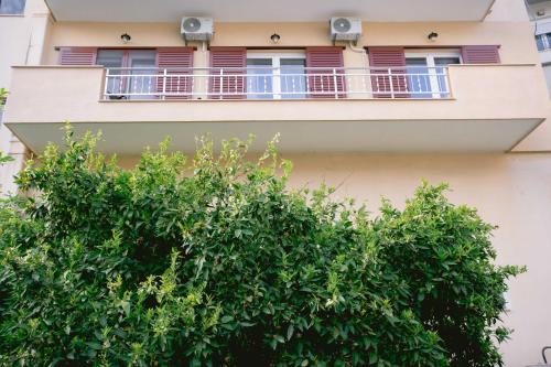 a building with a balcony and a tree at Κήπος μέ τις πορτοκαλιές in Mytilini