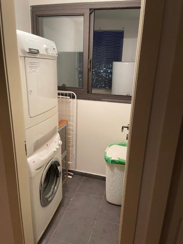 a laundry room with a washing machine and a window at Beautiful Penthouse w/amazing View, Prime location in Ramat Gan