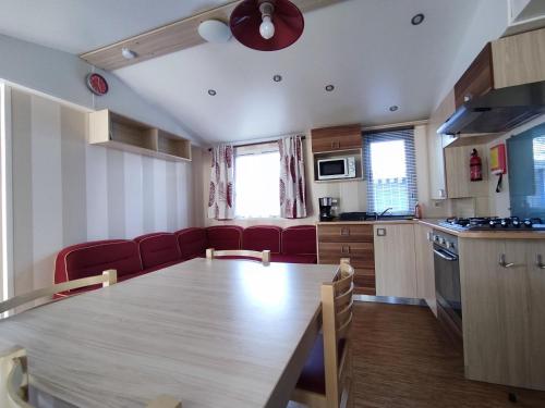 une cuisine avec une table en bois et des chaises rouges dans l'établissement Mobil Home à Meschers au camping l'Escale proche de Royan, à Meschers-sur-Gironde