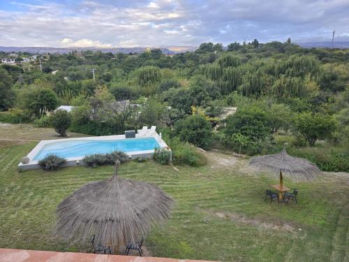 a house with a pool and two umbrellas at Los Molles Suites -Solo 2 Pax- in Mina Clavero