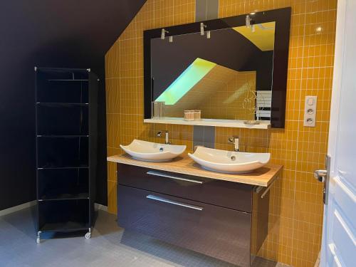une salle de bain avec deux lavabos et un grand miroir dans l'établissement Aux charmes de la campagne, à Millières