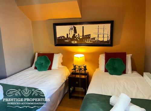 two beds in a room with a picture on the wall at Victoria Place by Prestige Properties SA in Workington