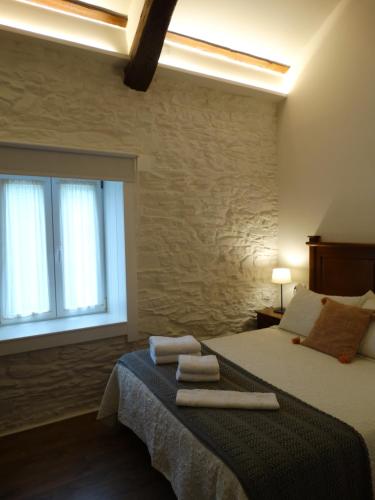 a bedroom with a bed with towels on it at Apartamentos Minas de Silvarosa in Viveiro