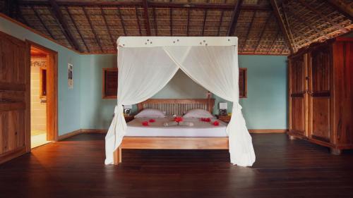 a bedroom with a bed with a canopy at Manja Kely Lodge in Nosy Be