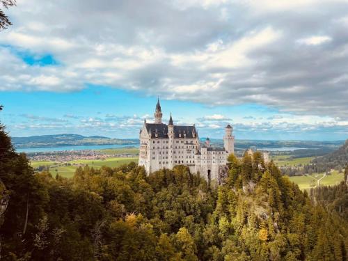 a castle on the top of a mountain at House LA Neuschwanstein Blick - Budget City Hotel in Füssen